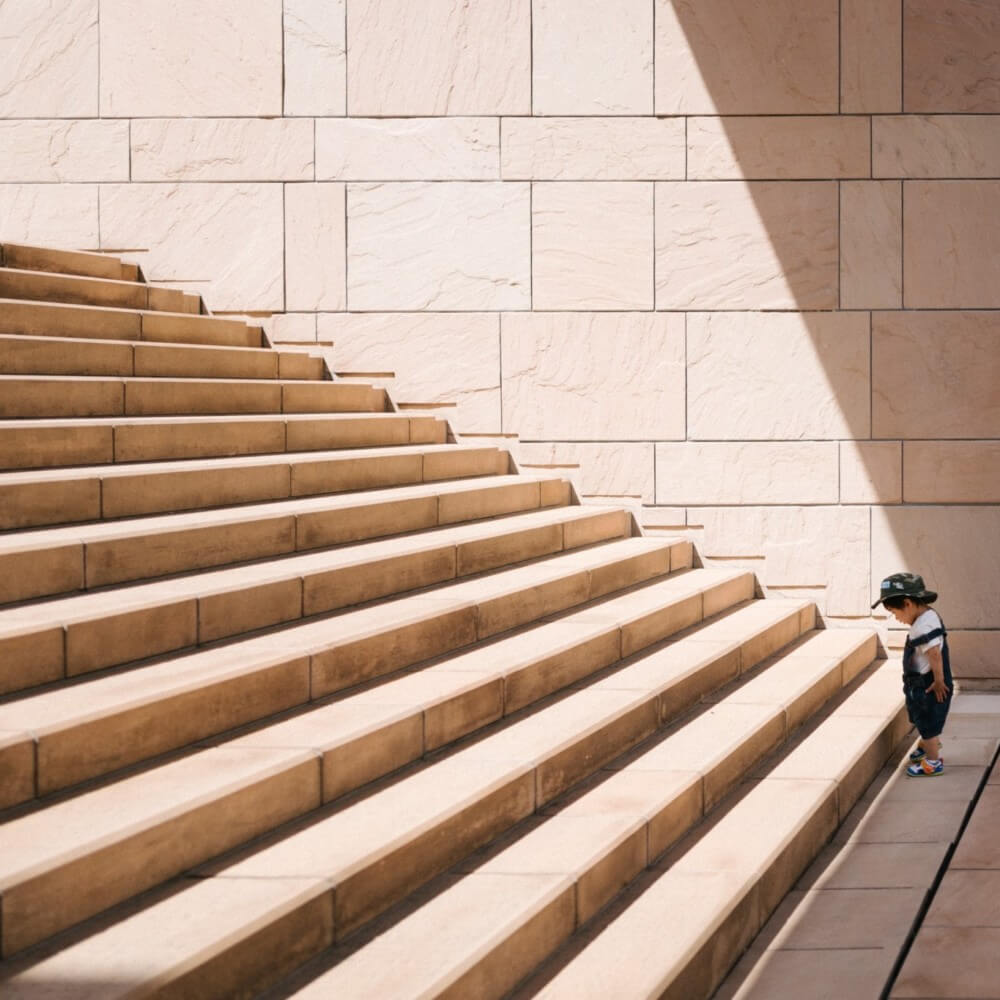 Kleiner Junge vor hellbrauner Treppe als Sinnbild für Google-Suchkampagnen