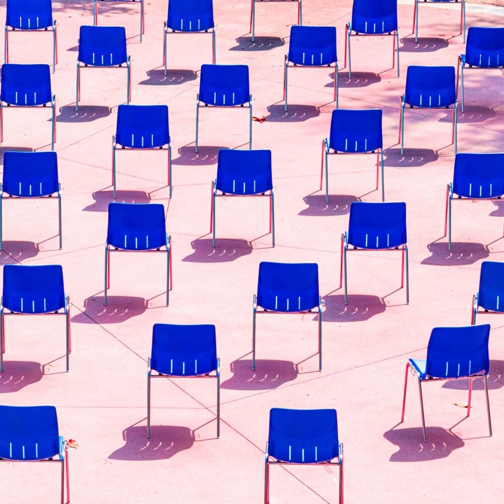 Viele blaue Stühle auf rosa Hintergrund